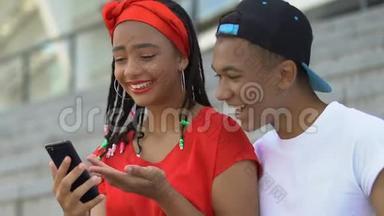 拥有智能手机的黑人青少年夫妇看着最后的派对照片，玩得很开心